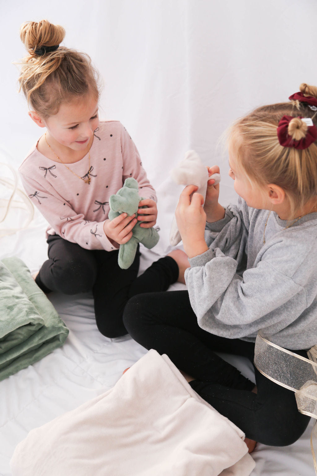 Two young girls playing with their therapy Bears on a bed.