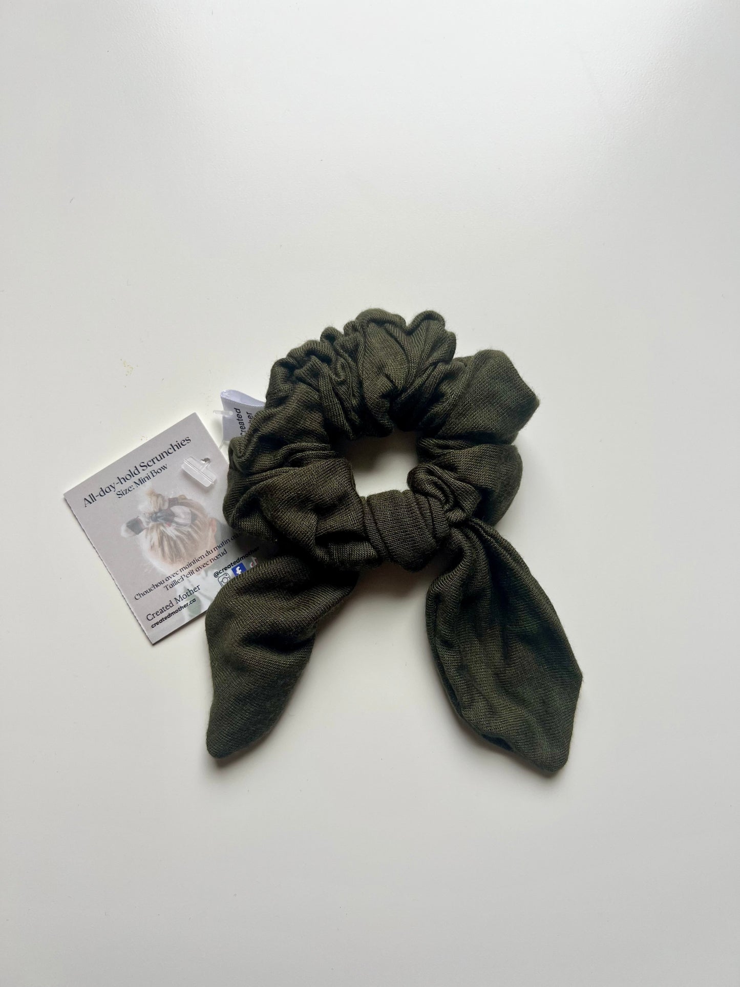 Green scrunchie on a white background with a business card.