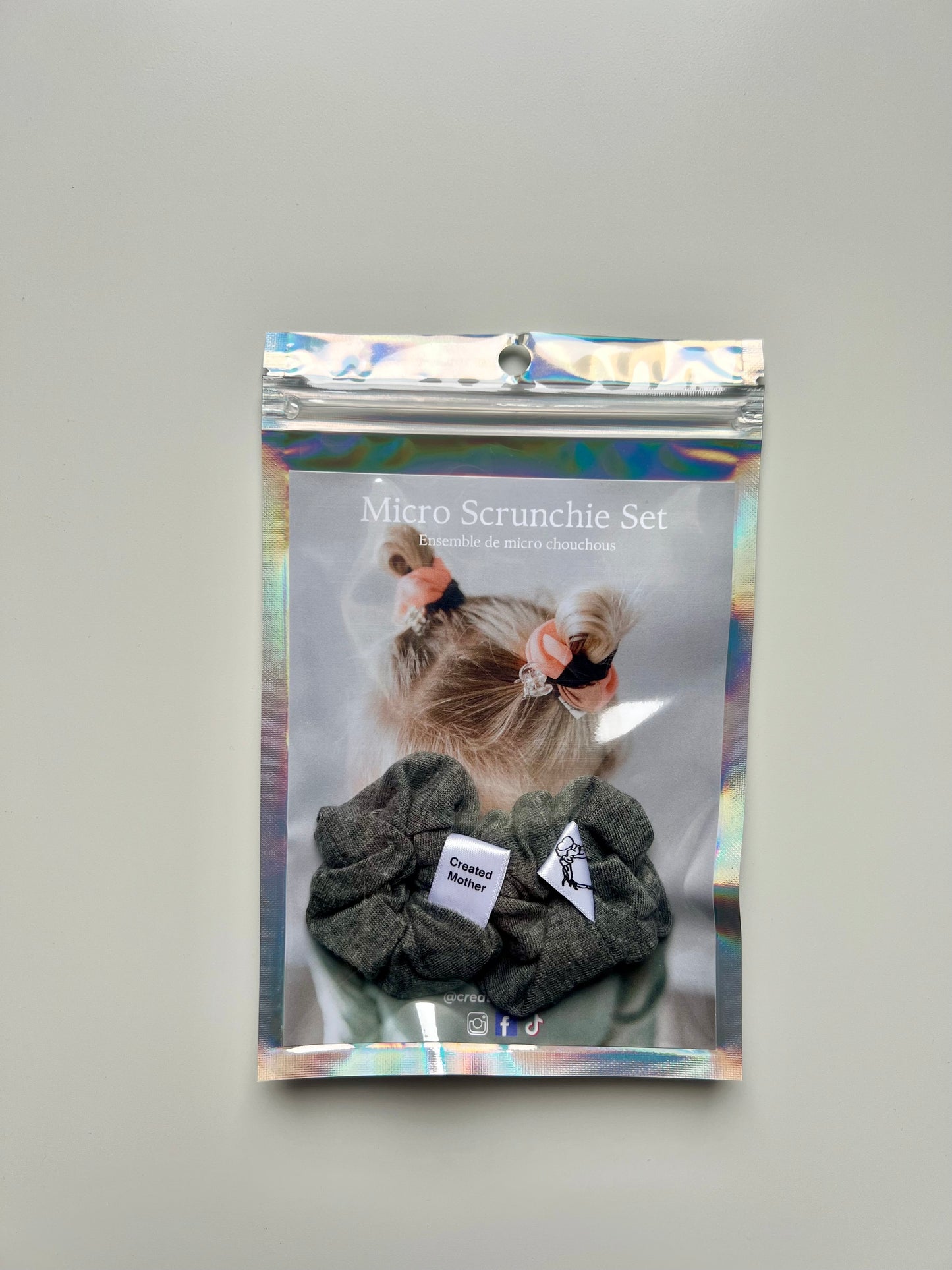 Packaged micro scrunchie set with gray scrunchies in a holographic bag.