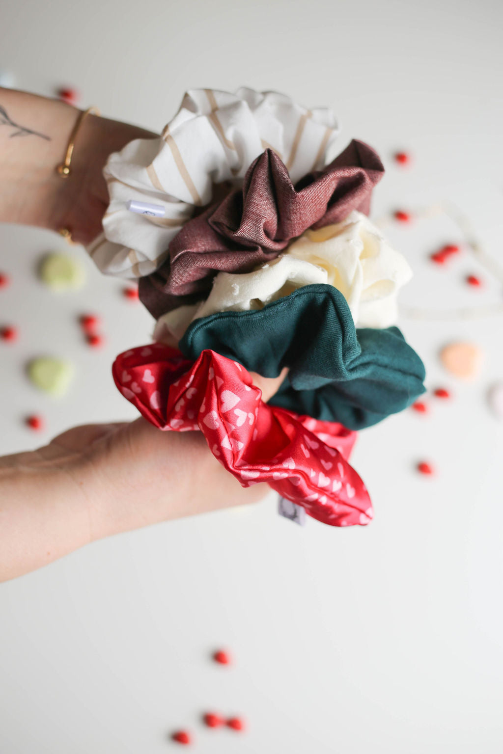 Set of colorful scrunchies held by a hand on a light background