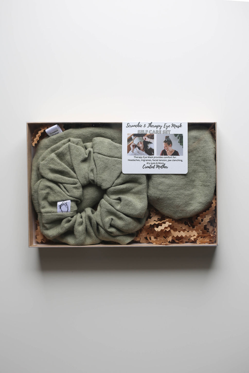 Close-up of hot/cold therapy eye mask resting on a linen pouch next to matching scrunchie.