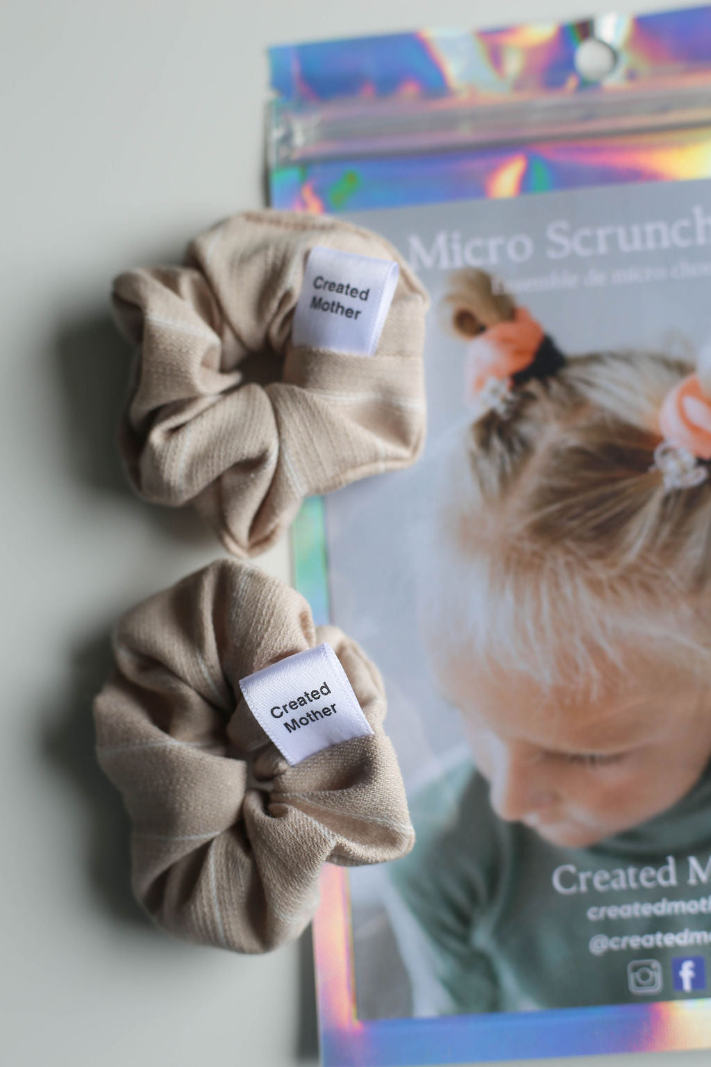 Two beige scrunchies with a branded poster in the background