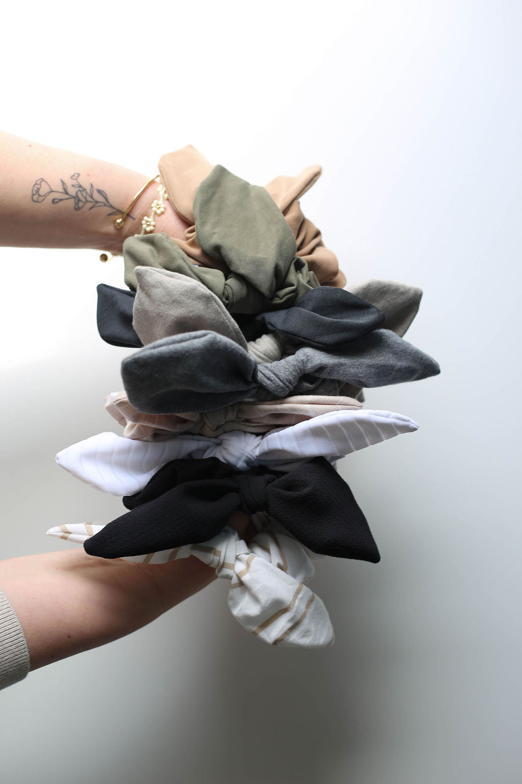 Hand holding a stack of colorful scrunchies against a plain background
