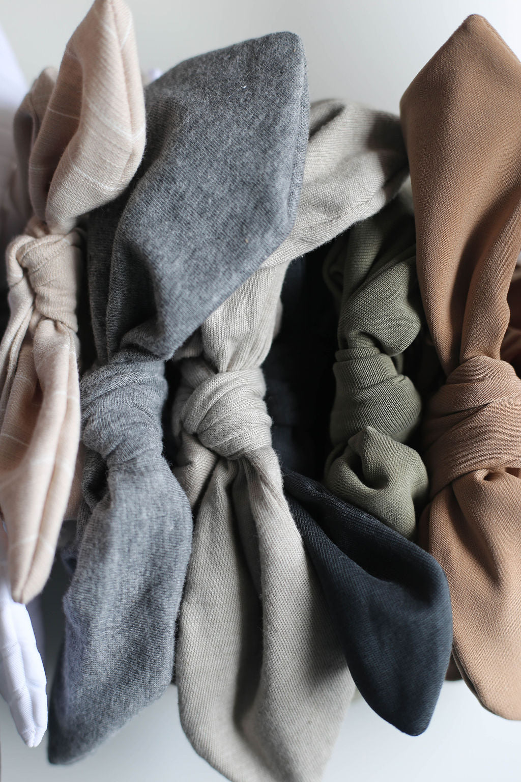 Set of knotted fabric hair ties in various neutral colors on a light background