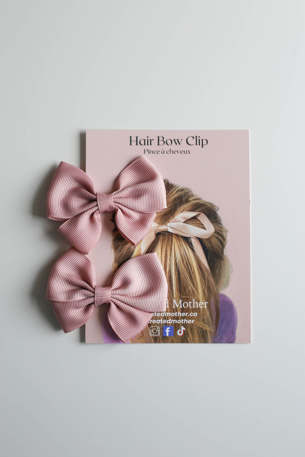 Charming mini ribbon bow in dusty rose, styled for casual or special occasion outfits.