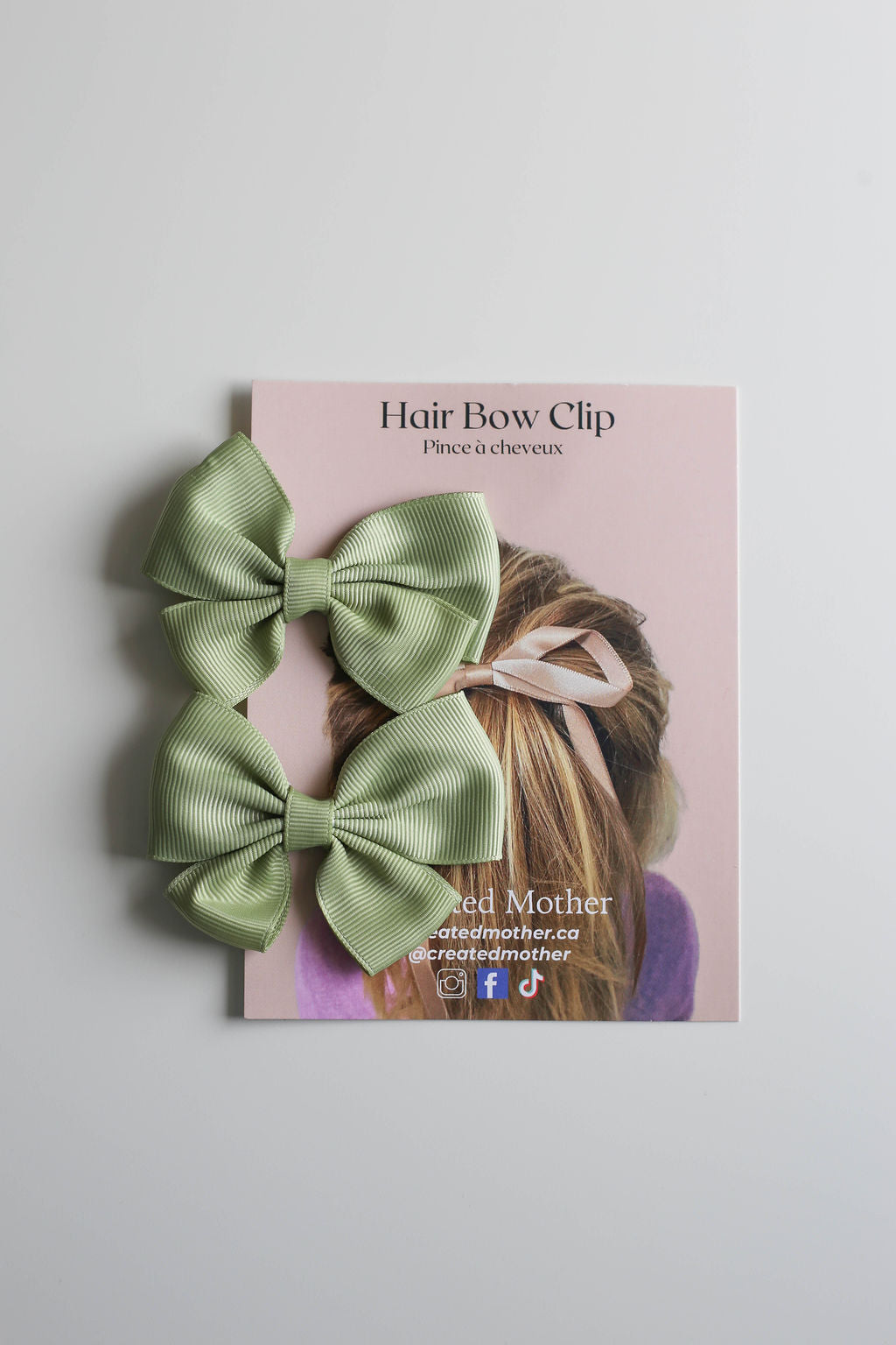Vibrant green hair bow made from premium ribbon, clipped to a sleek packaging card.