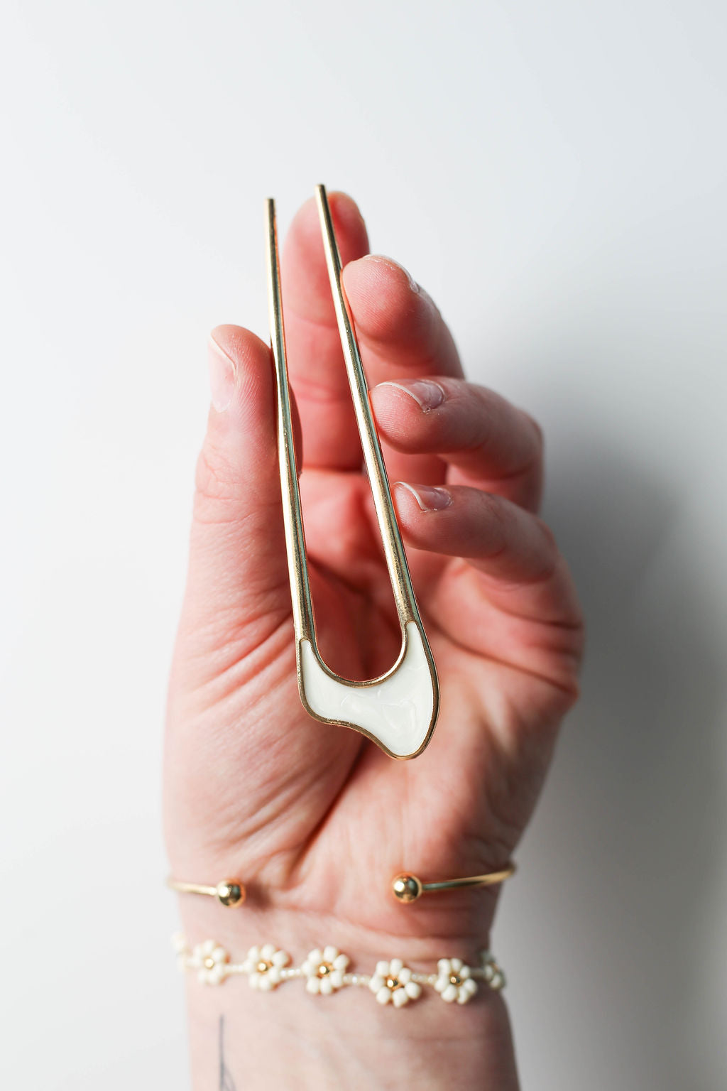 Minimalist metal hair accessory with sleek gold finish and white enamel detail.