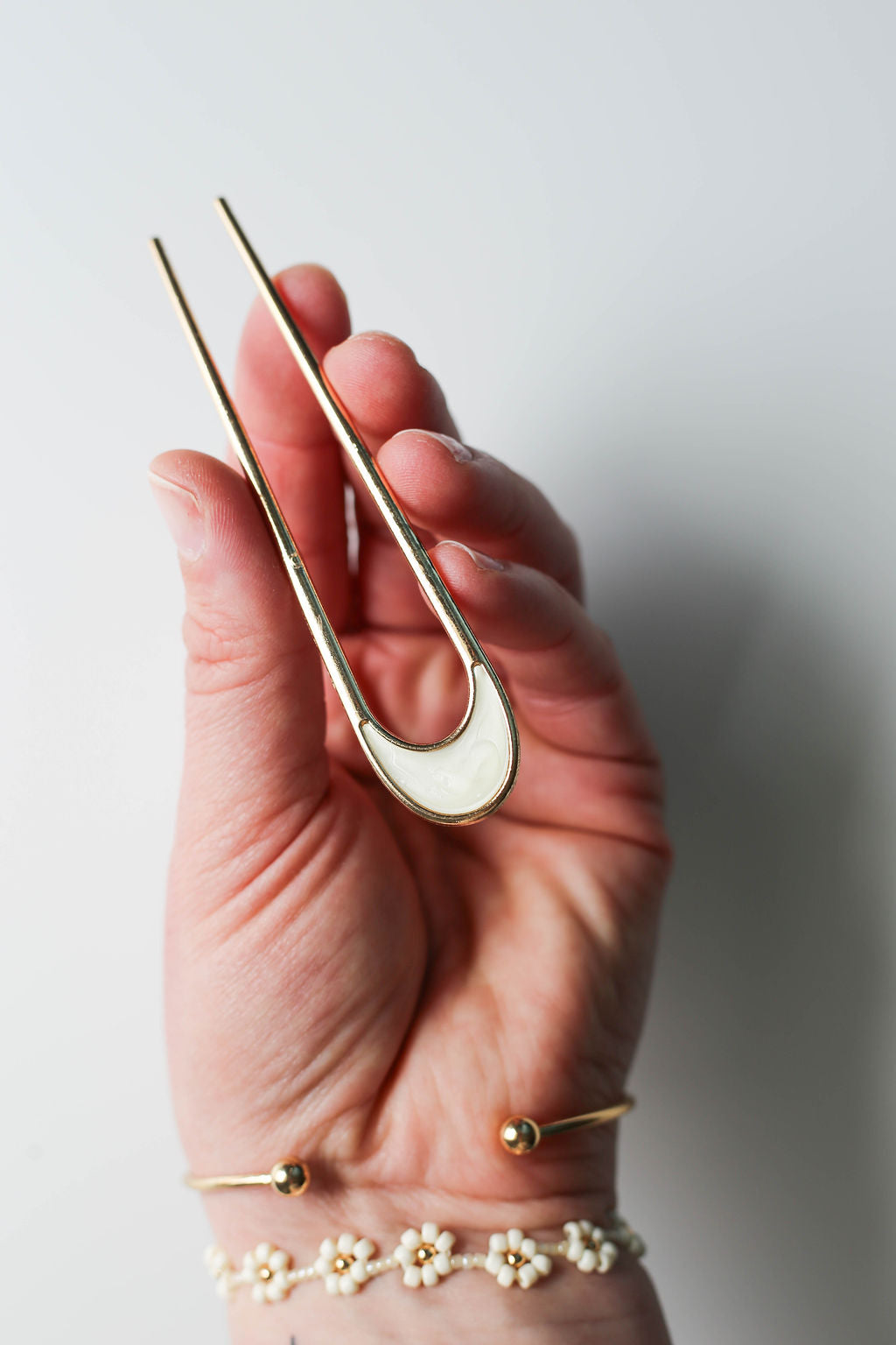 Gold U-shaped metal hair pin with white opalescent enamel accent.
