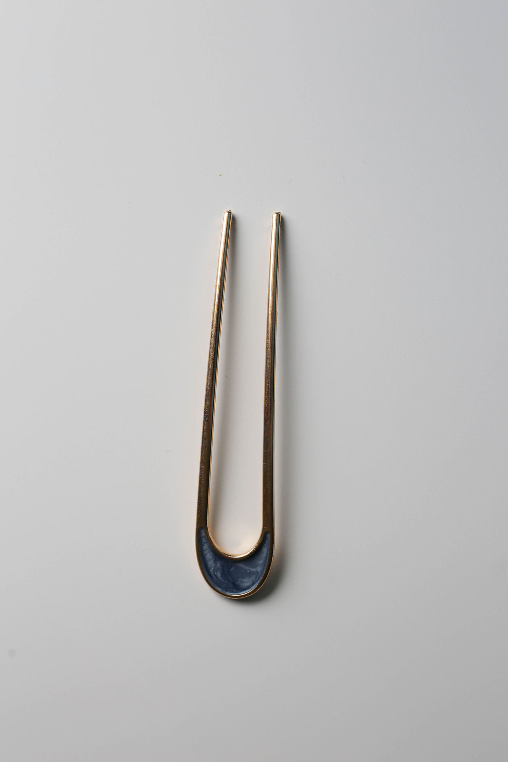 Minimalist hair styling pin, gold with shimmering blue detail.
