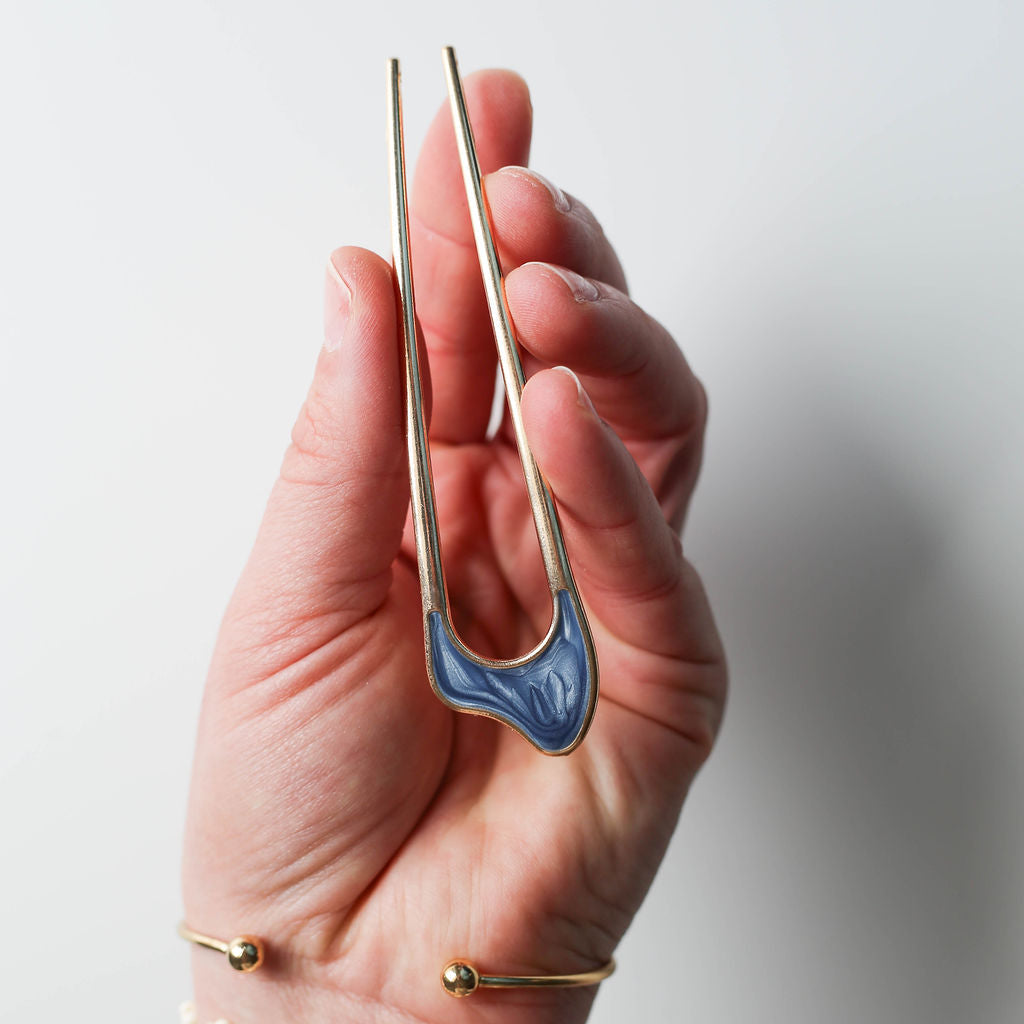 Gold U-shaped hair pin with blue opalescent enamel accent.