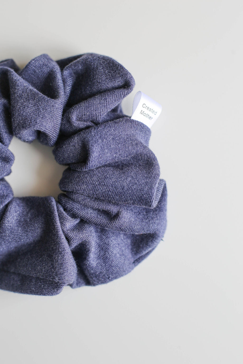 Blue scrunchie with a label on a light gray background