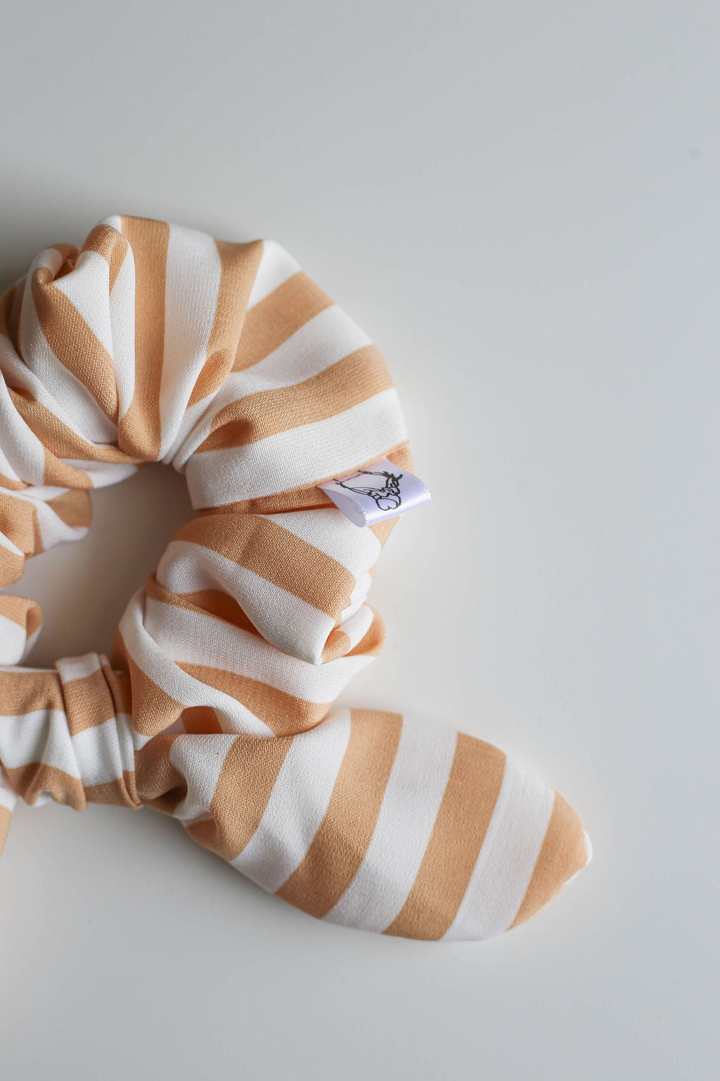 Striped scrunchie with a brand label on a light gray background