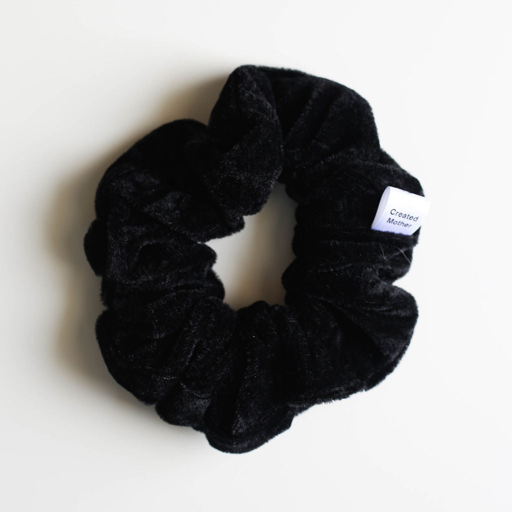 Black scrunchie with a brand label on a white background