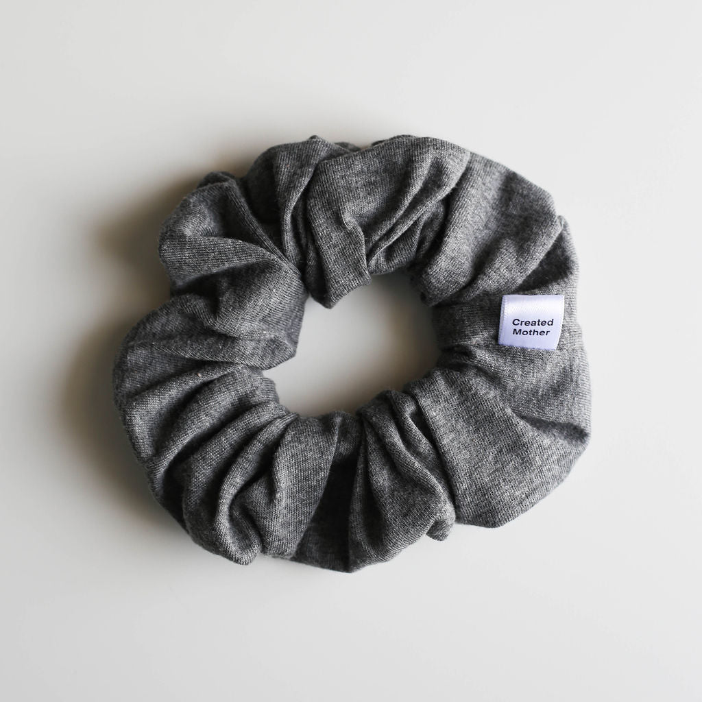Gray scrunchie with a brand label on a light gray background
