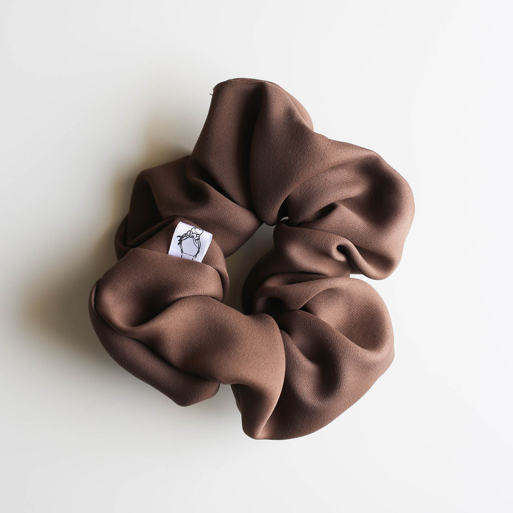 Brown scrunchie with a brand label on a white background