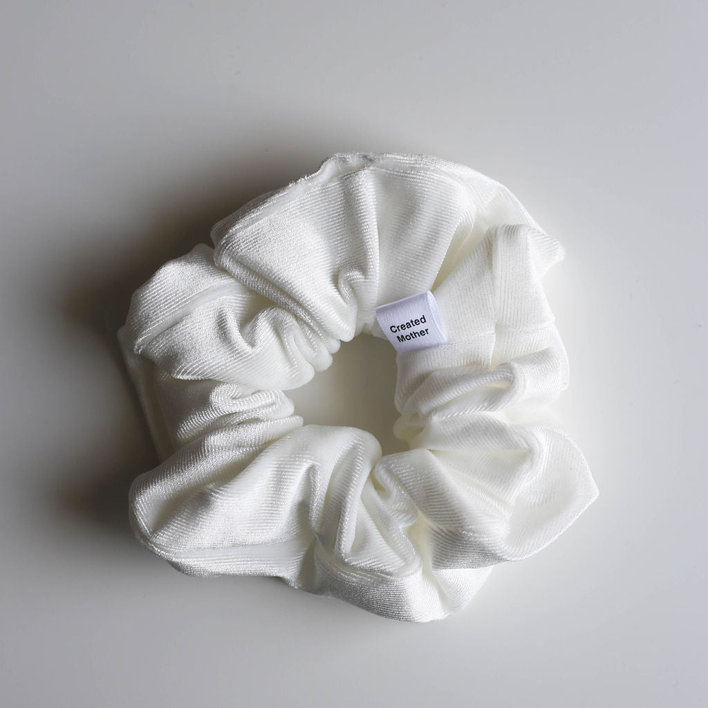 White scrunchie with a label on a light gray background
