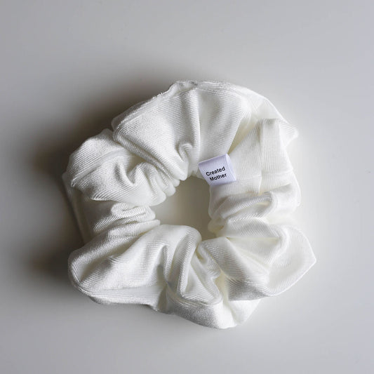 White scrunchie with a label on a light gray background