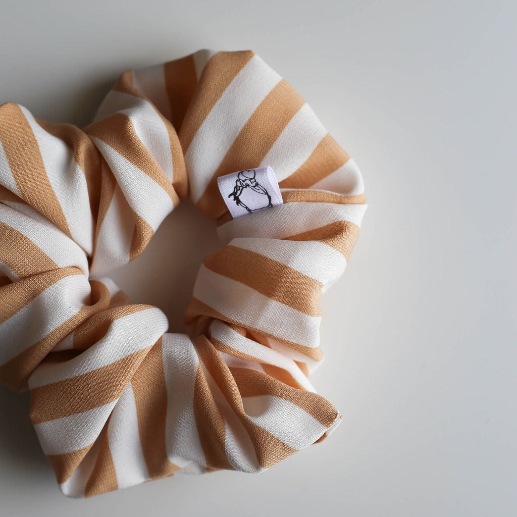 Striped scrunchie with a brand label on a light gray background