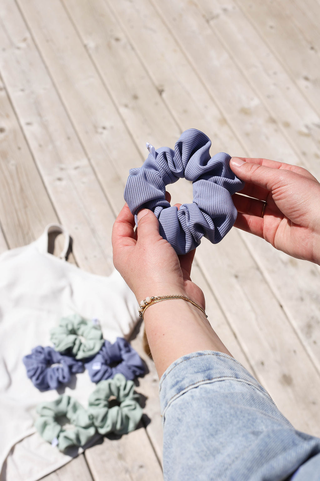 Person holding a blue scrunchie with scrunchies in the background