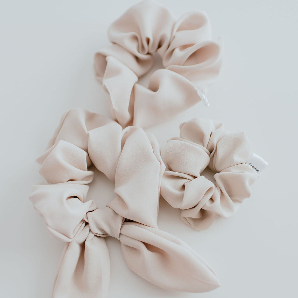 Set of beige scrunchies on a light gray background