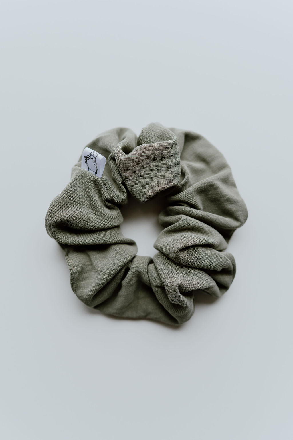 Green scrunchie with a brand label on a light gray background
