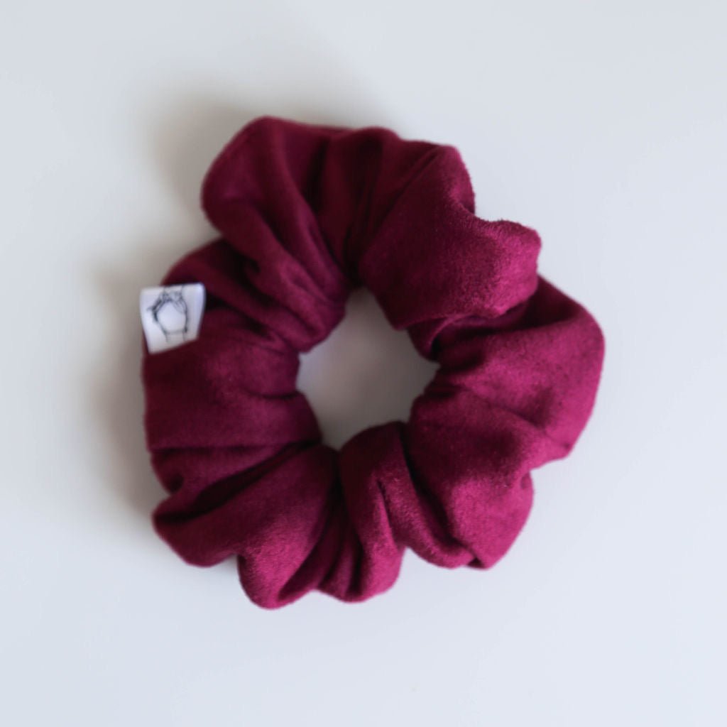 A rich berry-colored suede scrunchie with a smooth texture, handmade for all-day hold and comfort.