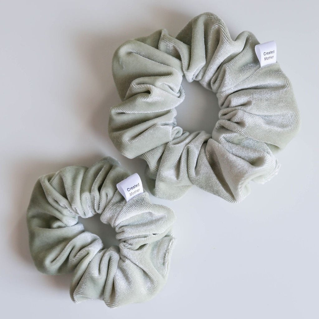 A soft, sage green velvet scrunchie with a plush texture, locally handmade for all hair types.