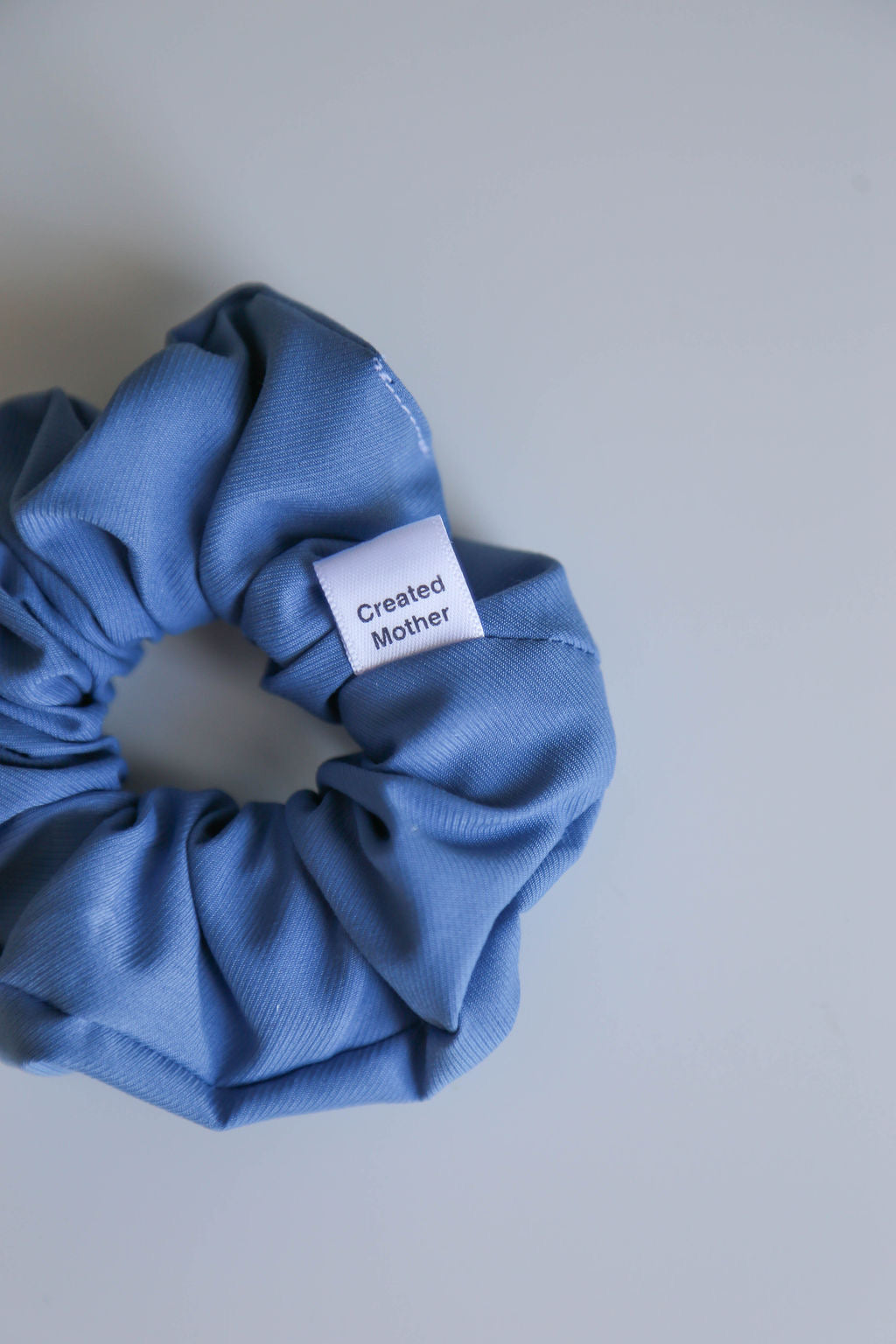 Handcrafted blue scrunchie with a soft texture, adding elegance to any hairstyle.