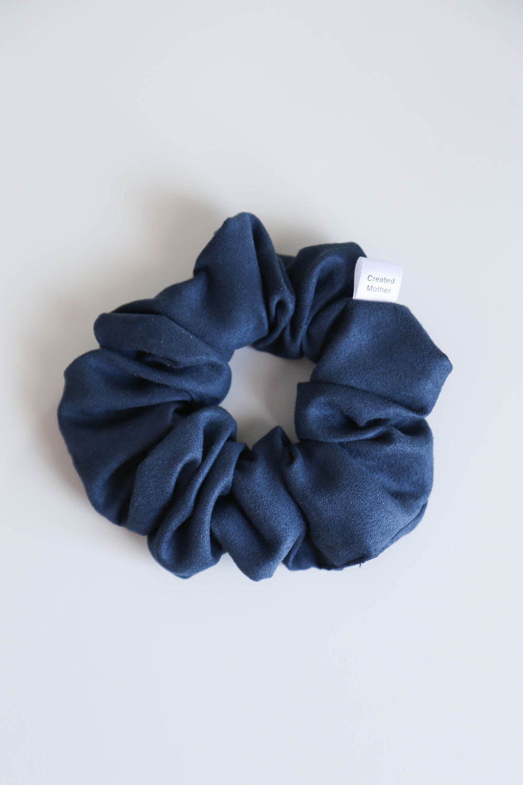 Ocean-inspired blue suede scrunchie with soft, smooth fabric, perfect for all hair types and occasions