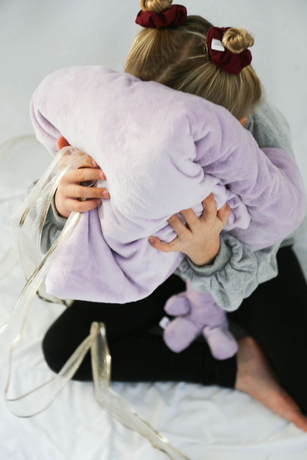 Child hugging a large lavender cozy blanket with a matching hot/cold therapy pack on her lap