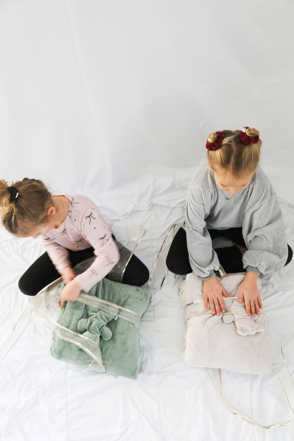 Two children sitting on a bed opening their Bear and Blanket gift set by Created Mother