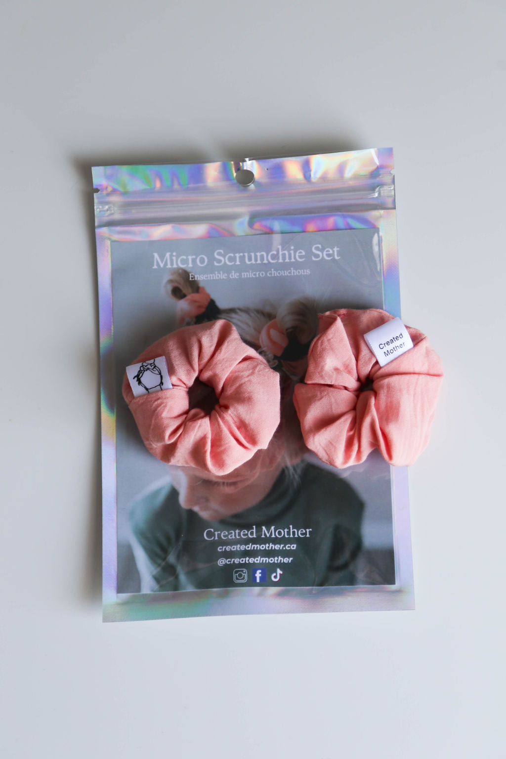 Package of pink scrunchies with a brand label on a light gray background