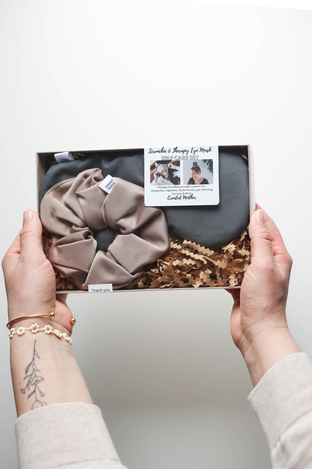 Flat lay of self-care gift set with cotton blend eye mask and scrunchie on a cozy knit background.
