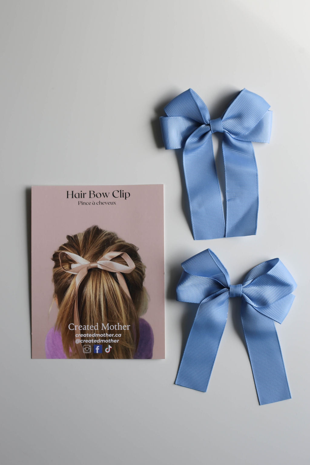 Oversized ribbon bow clip in blush pink displayed on a branded card for retail or gifting.