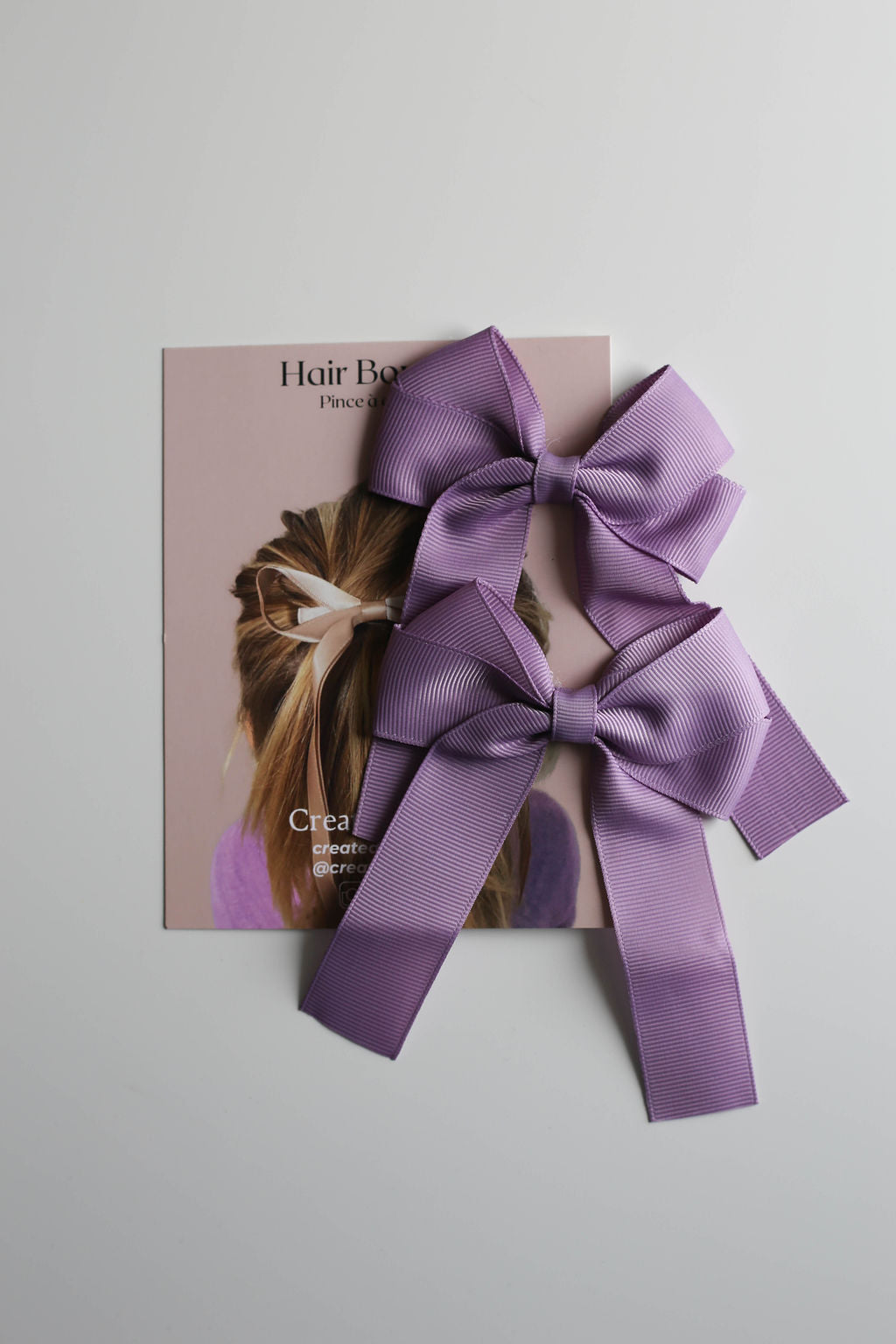 Stylish oversized bow in purple shown on display card, perfect for boutiques and salons.