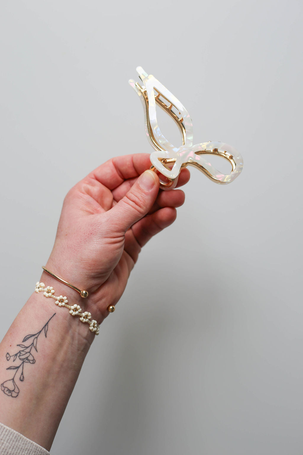 Large metal bow hair claw clip with pearly white eco acetate and gold-tone frame.