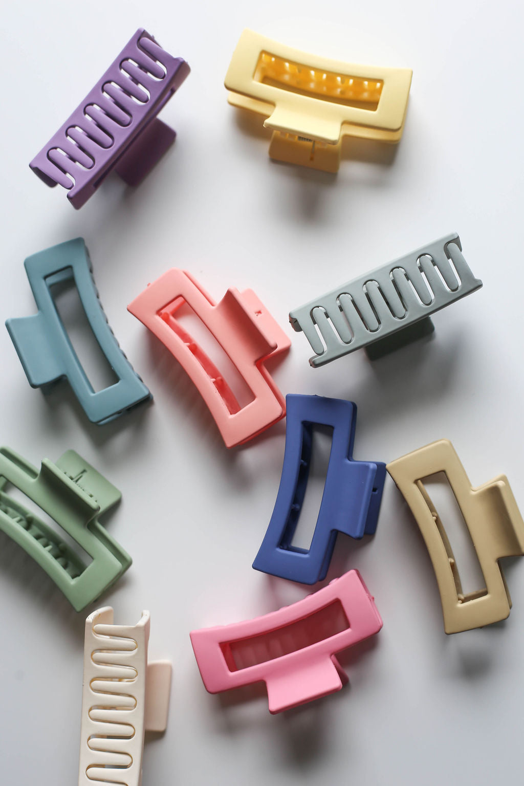 Overhead flat lay of nine assorted small claw clips in bright, fun colours on a white background.