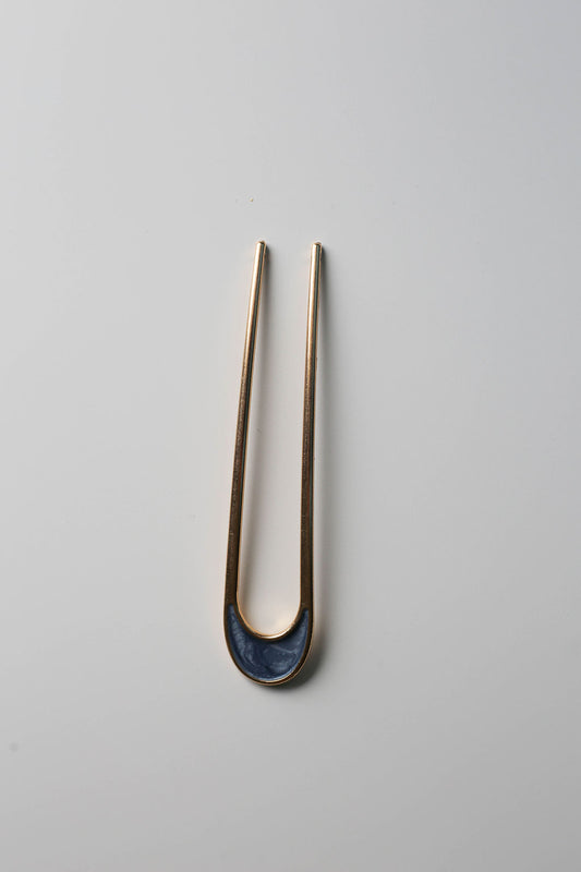 Minimalist hair styling pin, gold with shimmering blue detail.