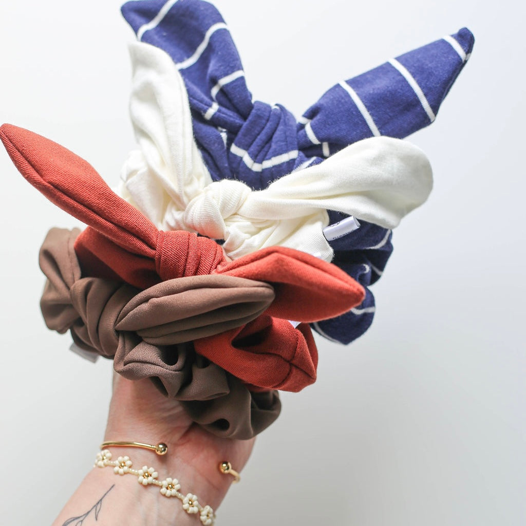 Colorful scrunchies held in a hand against a white background