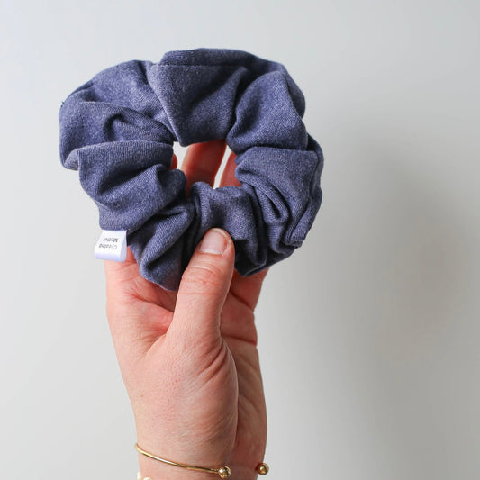 Gentle blue scrunchie held in hand with floral tattoo