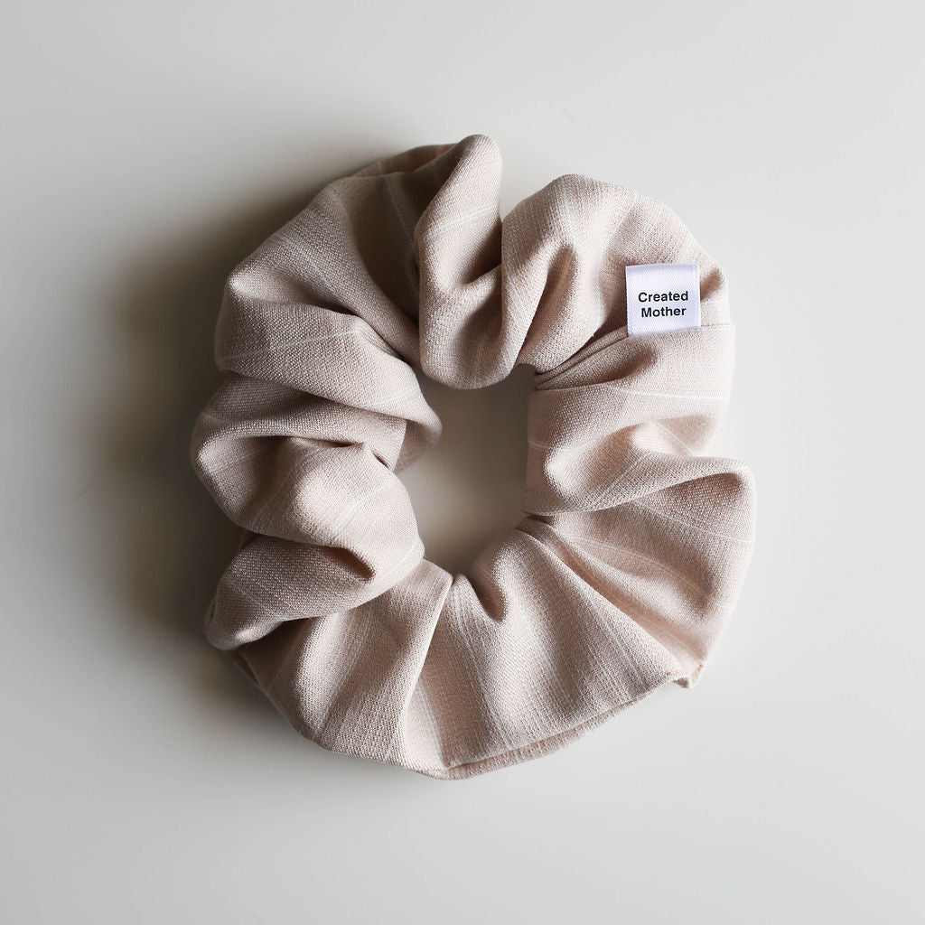 Beige scrunchie with a label on a light gray background