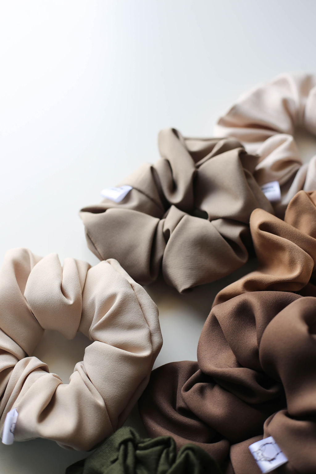 Set of beige, brown, and green scrunchies on a white background