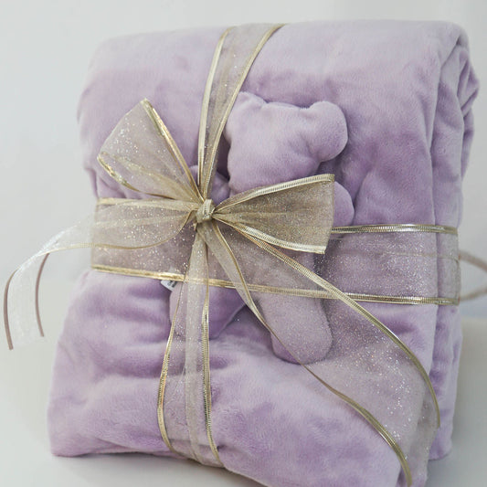 Purple plush blanket and matching comfort bear with a gold bow on a white background