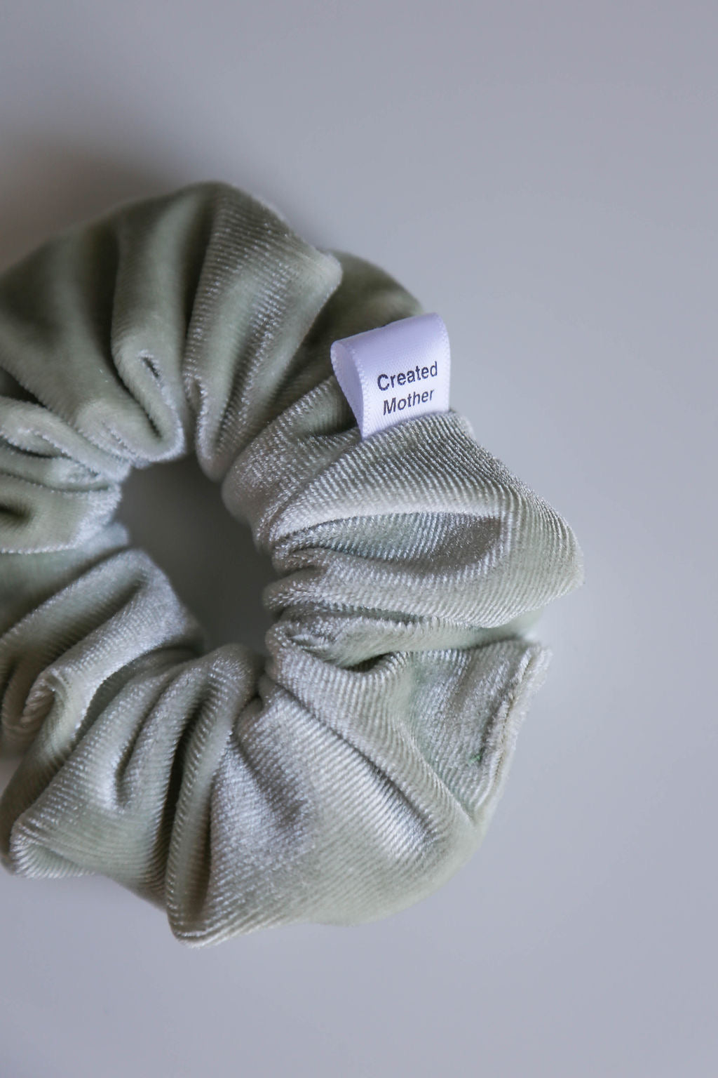 Close-up of the Eucalyptus Dream Velvet Scrunchie in light sage green with a rich, elegant sheen.