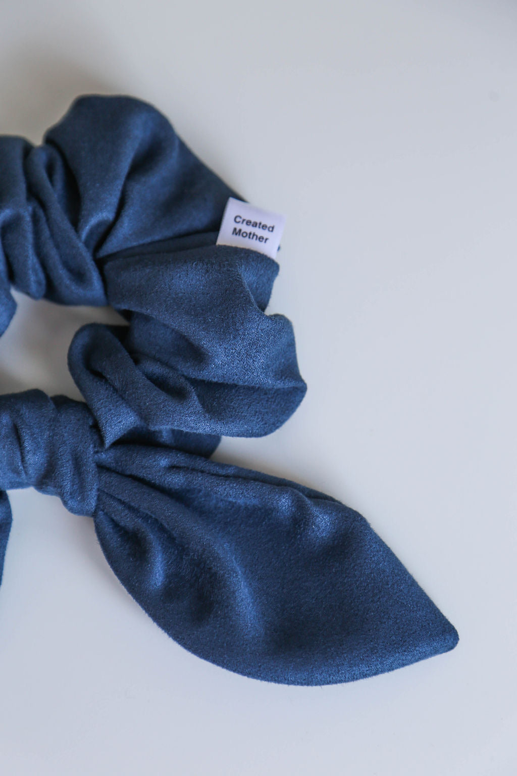 Handcrafted blue suede scrunchie with a velvety texture, designed for secure and comfortable styling.