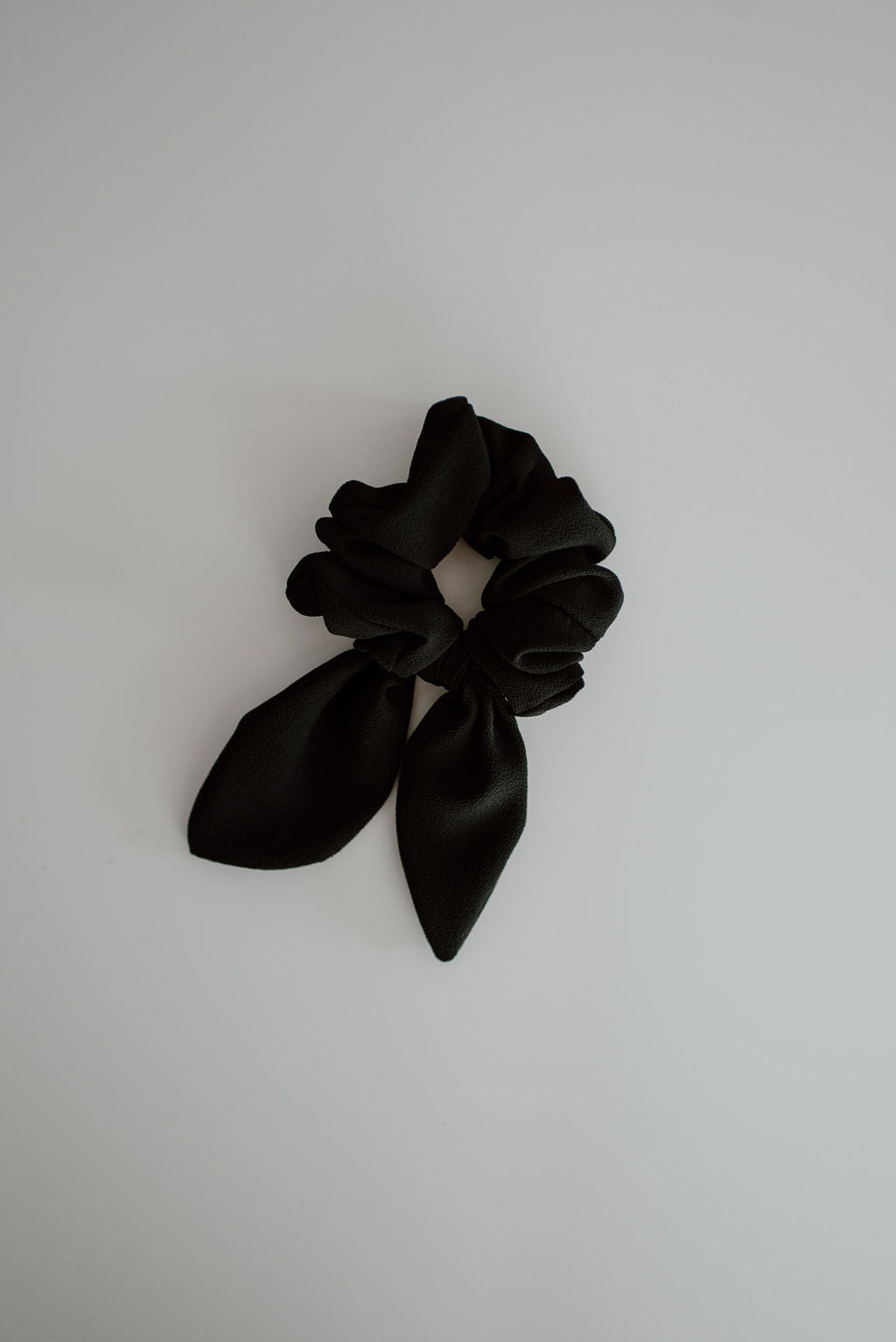 Black scrunchie with a bow on a light gray background