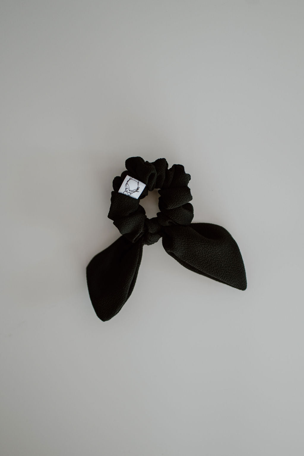 Mini Black scrunchie with bow on a light gray background