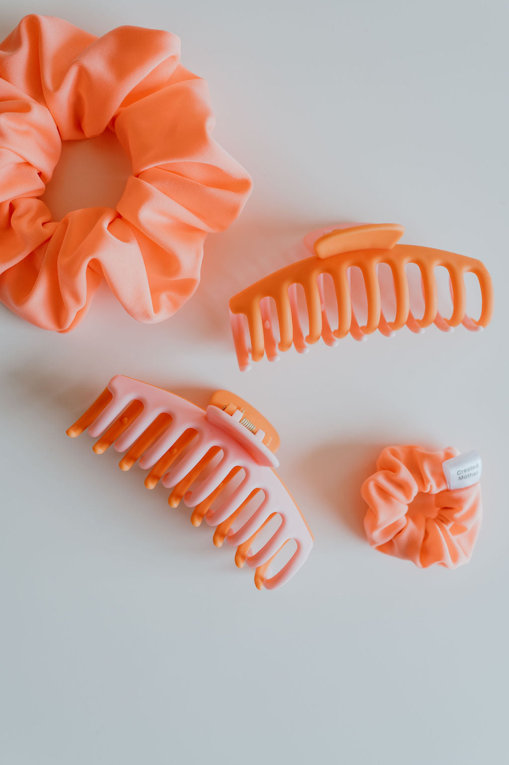 Set of orange hair accessories including scrunchies and clips on a white background